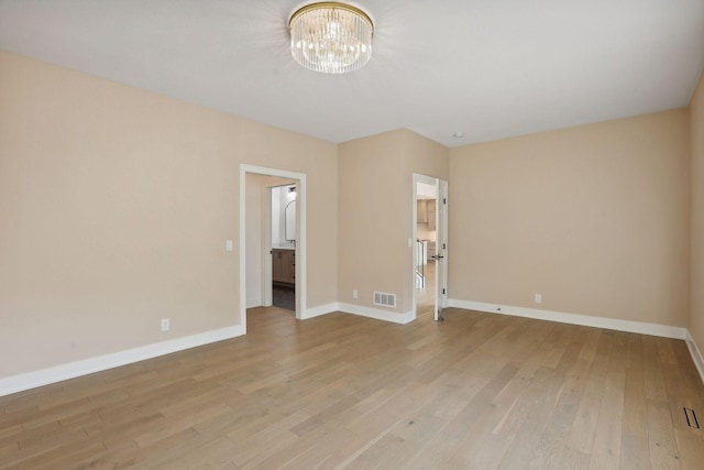 empty room with light hardwood / wood-style flooring and a notable chandelier