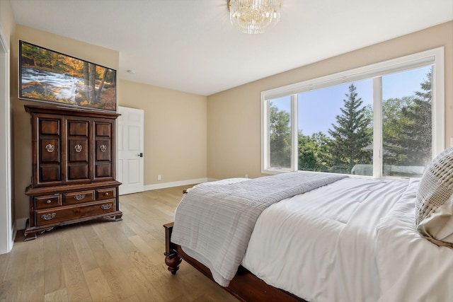 bedroom featuring light wood-type flooring and an inviting chandelier