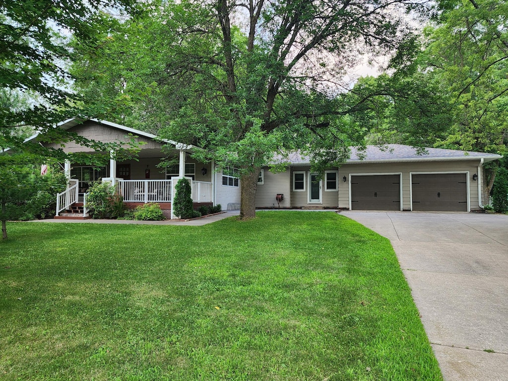 view of front facade with a garage, covered porch, and a front lawn