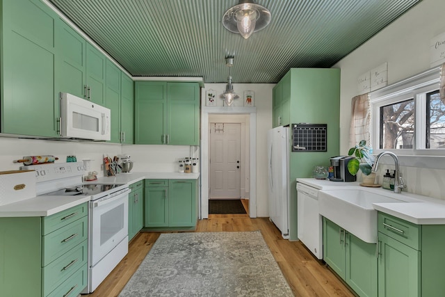 kitchen with white appliances, decorative light fixtures, sink, green cabinetry, and light wood-type flooring