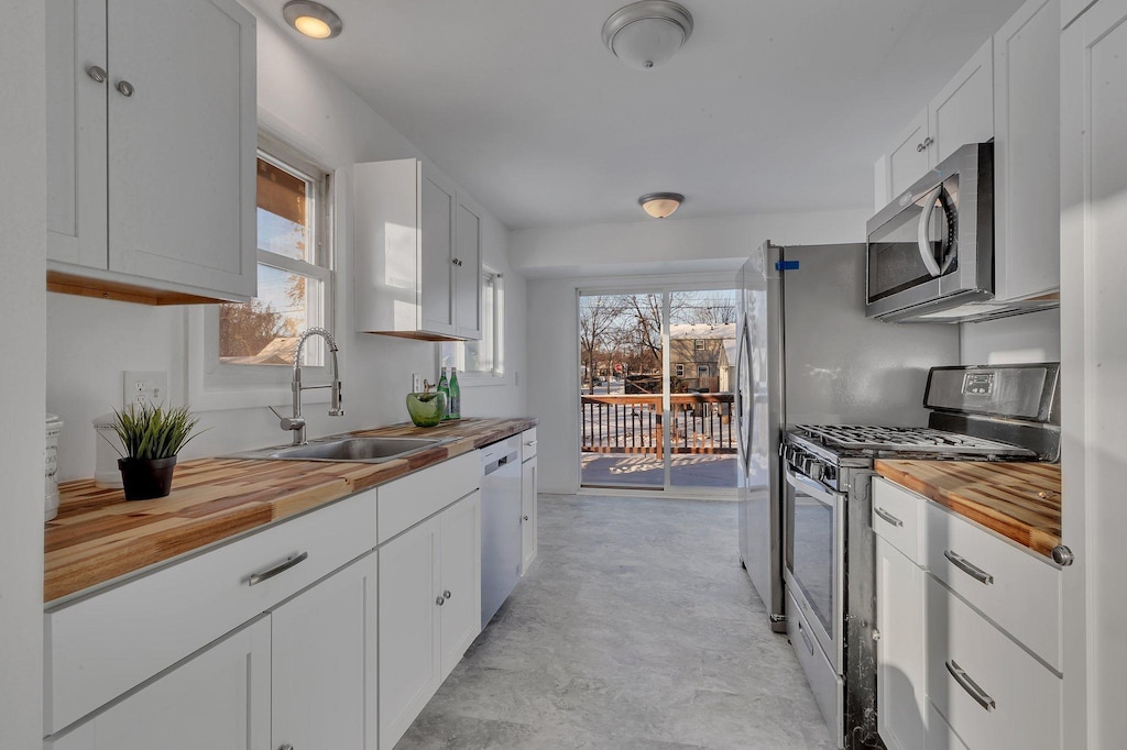 kitchen featuring white cabinets, butcher block countertops, sink, and stainless steel appliances