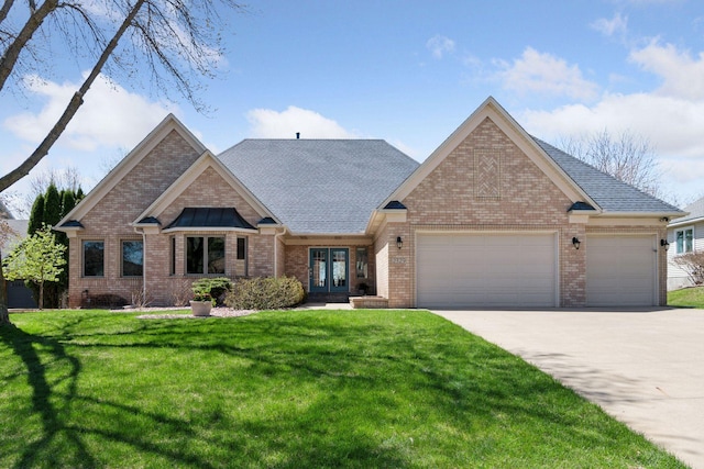 view of front facade with a front yard, french doors, brick siding, concrete driveway, and an attached garage