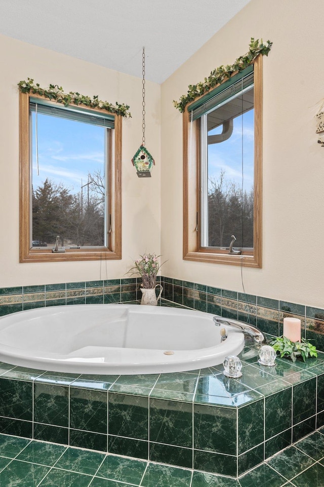 bathroom featuring a wealth of natural light and tiled bath