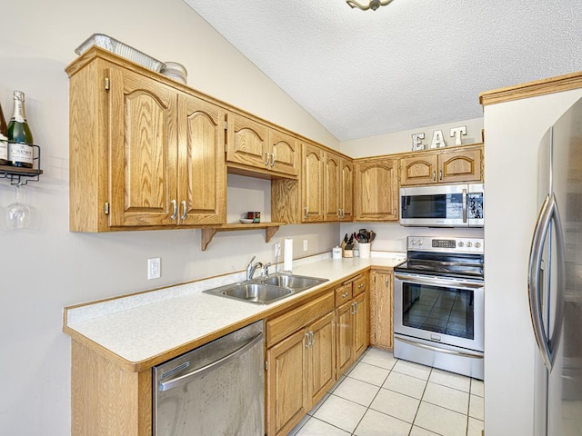 kitchen with lofted ceiling, sink, appliances with stainless steel finishes, a textured ceiling, and light tile patterned flooring