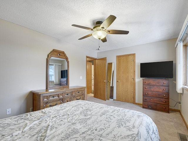 carpeted bedroom with ceiling fan and a textured ceiling