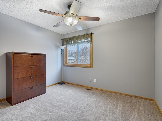 unfurnished bedroom featuring ceiling fan, light colored carpet, and a textured ceiling