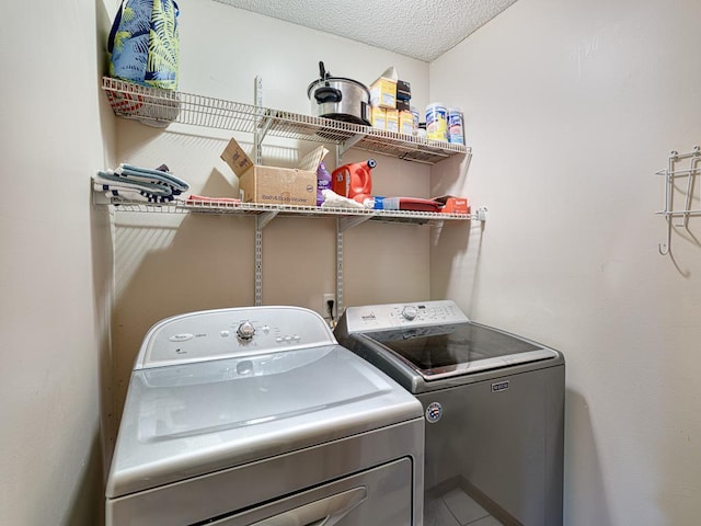 clothes washing area with washer and dryer and a textured ceiling