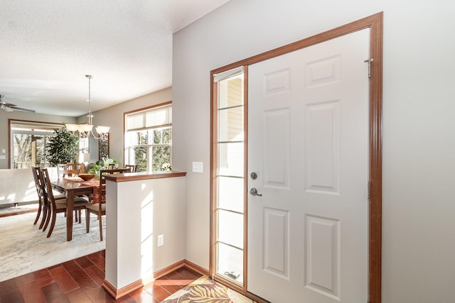 foyer entrance featuring an inviting chandelier, wood-type flooring, and a textured ceiling