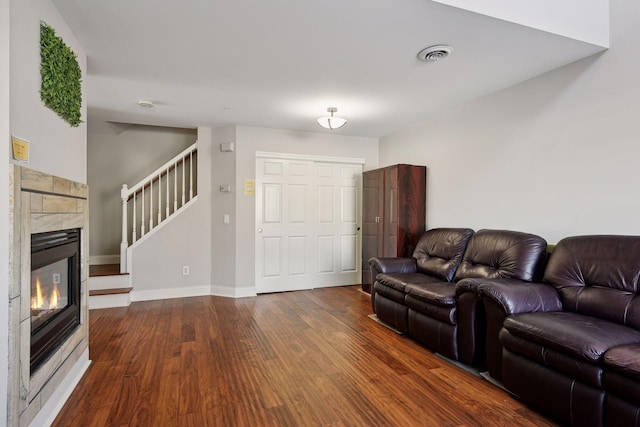 living room with a tile fireplace and dark hardwood / wood-style flooring