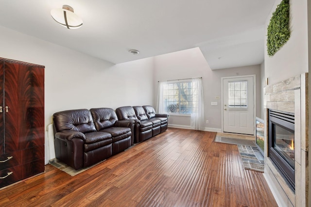 living room with dark hardwood / wood-style flooring and a tiled fireplace