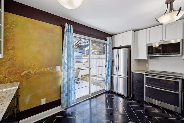 kitchen featuring light stone countertops, white cabinetry, appliances with stainless steel finishes, and dark tile patterned floors