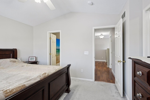 carpeted bedroom with ensuite bathroom, lofted ceiling, and ceiling fan