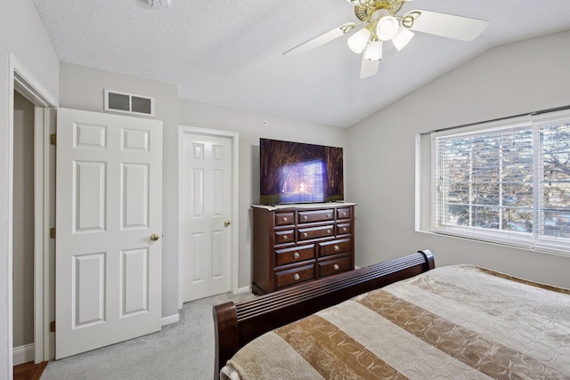 bedroom featuring ceiling fan, vaulted ceiling, light carpet, and a textured ceiling