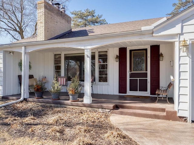 doorway to property featuring board and batten siding, a porch, a chimney, and a shingled roof