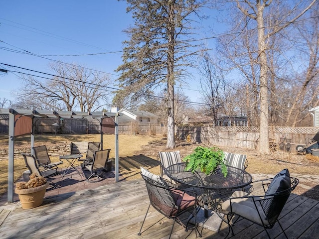 deck featuring a storage shed, outdoor dining area, a fenced backyard, and an outbuilding