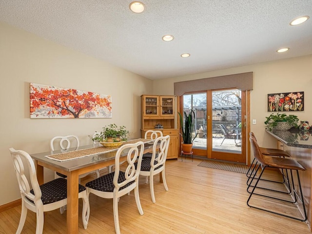 dining area featuring light wood-style flooring, recessed lighting, baseboards, and a textured ceiling