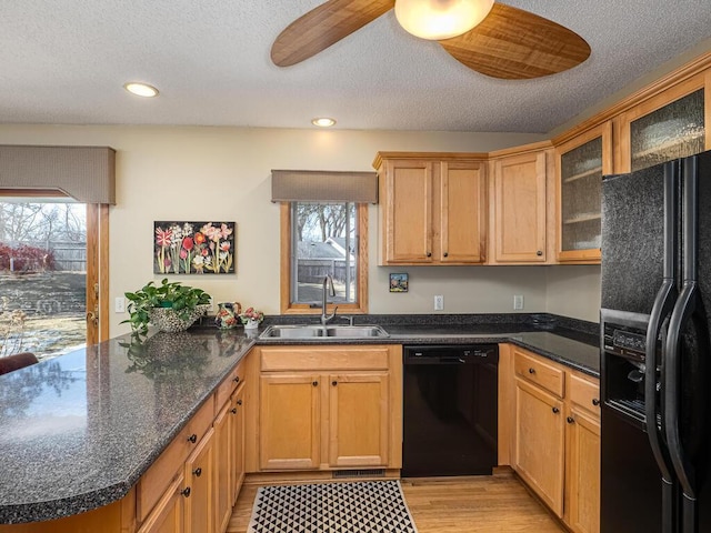 kitchen featuring black appliances, a peninsula, a wealth of natural light, and a sink