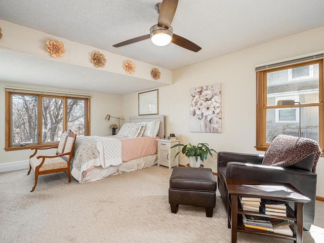 carpeted bedroom featuring multiple windows, a textured ceiling, and a ceiling fan