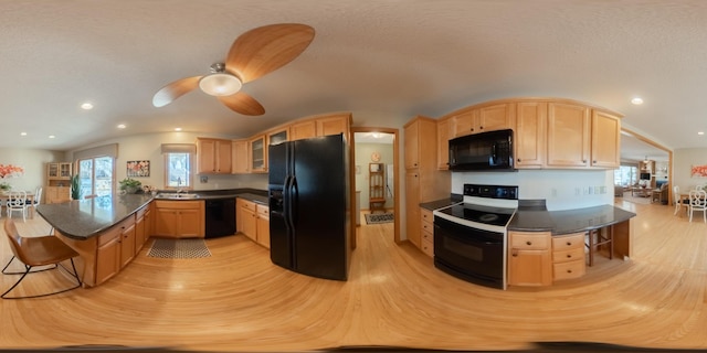 kitchen with light brown cabinets, a peninsula, a sink, black appliances, and a wealth of natural light