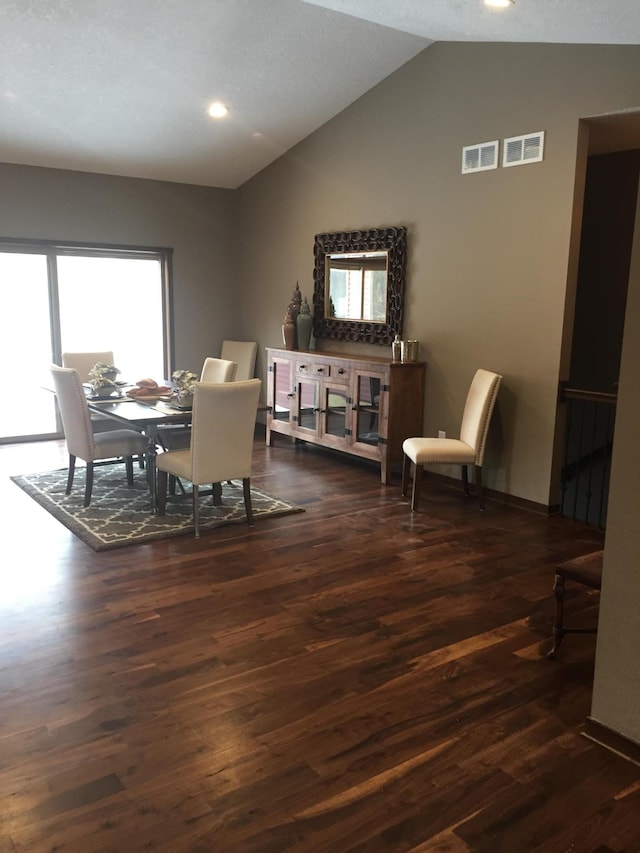 dining area with dark wood-type flooring and vaulted ceiling