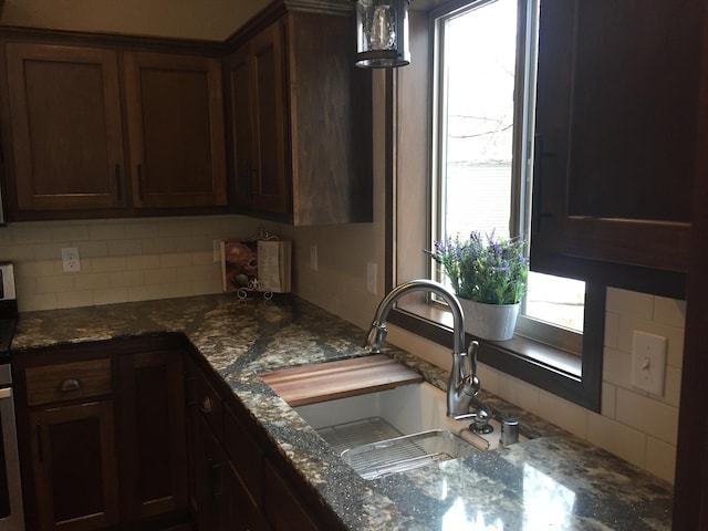 kitchen with decorative backsplash, plenty of natural light, sink, and dark stone countertops