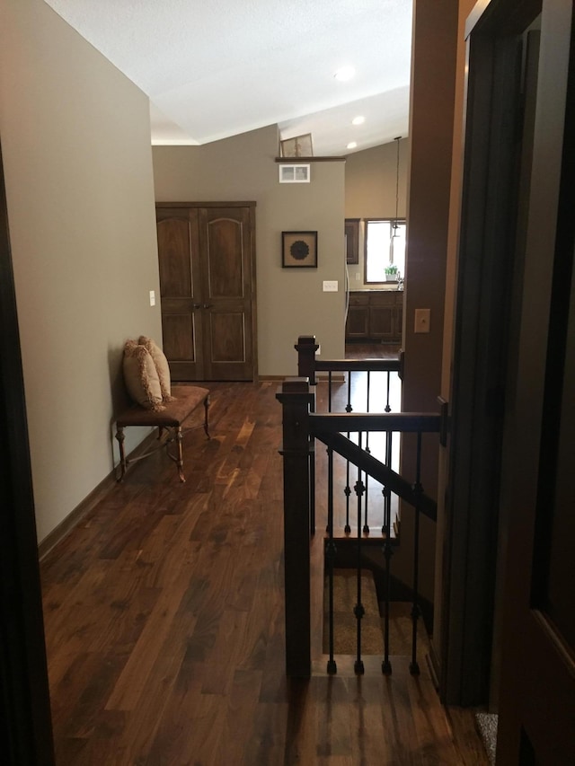 hallway featuring dark wood-type flooring and vaulted ceiling