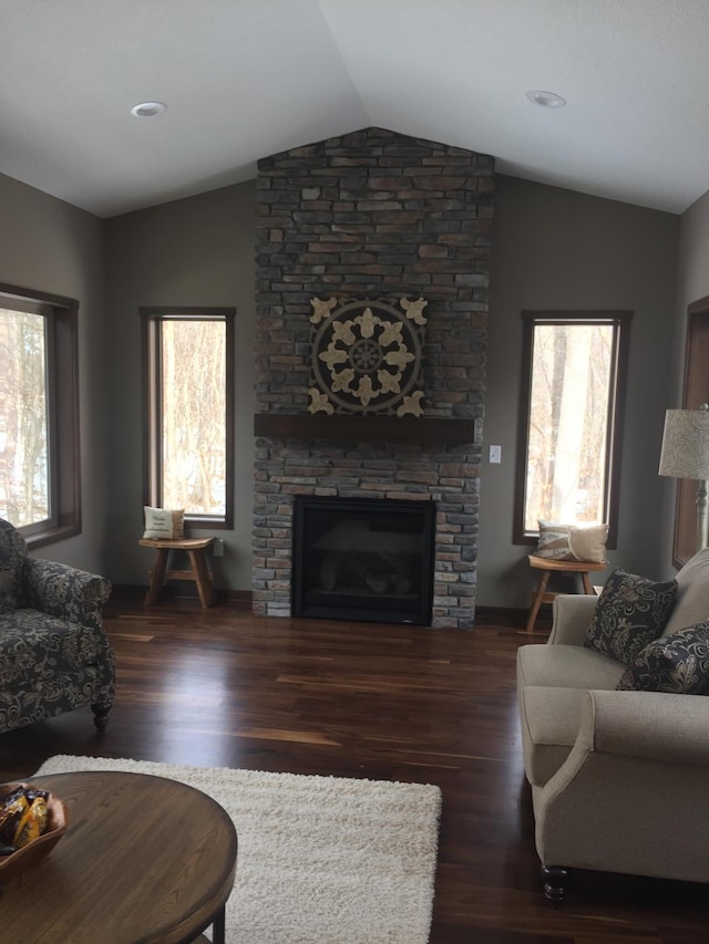 living room featuring vaulted ceiling, dark wood-type flooring, and a fireplace