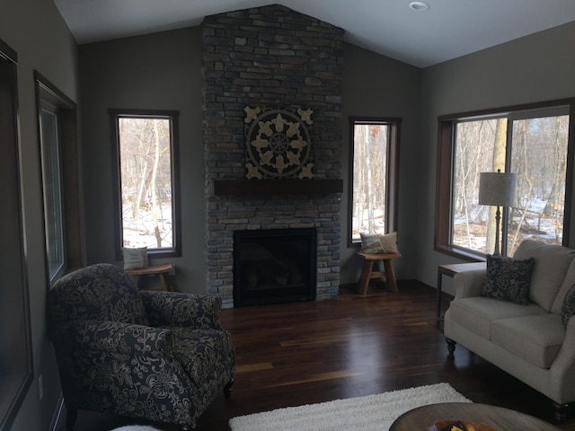 living room with plenty of natural light, lofted ceiling, and a stone fireplace