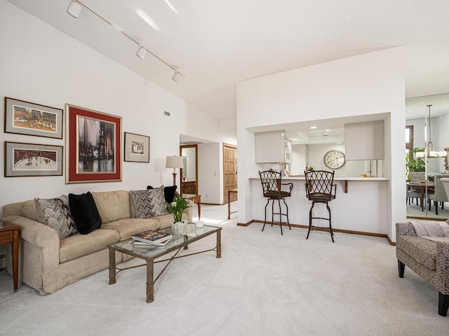 living room with baseboards, light carpet, and rail lighting