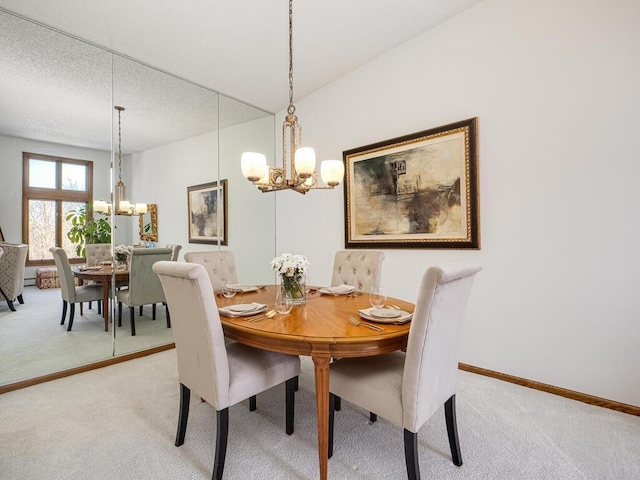 dining room with a notable chandelier, baseboards, and light colored carpet