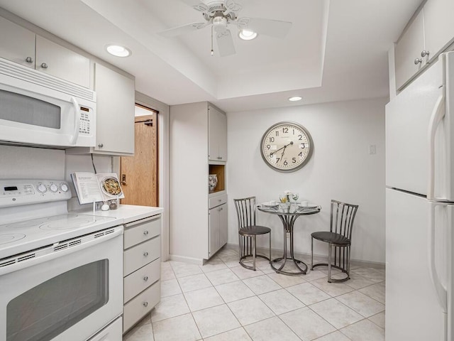 kitchen featuring light tile patterned floors, recessed lighting, white appliances, and a tray ceiling