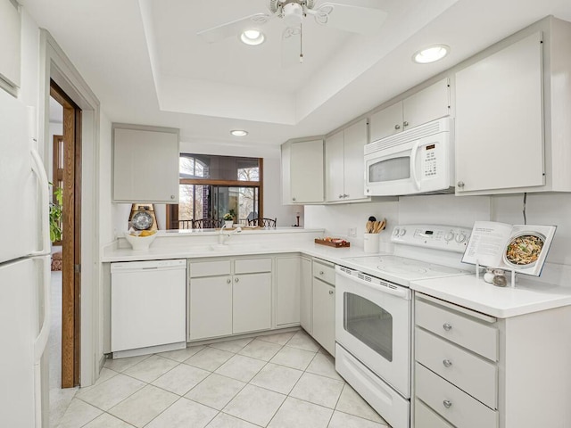 kitchen with light countertops, recessed lighting, light tile patterned flooring, white appliances, and a raised ceiling