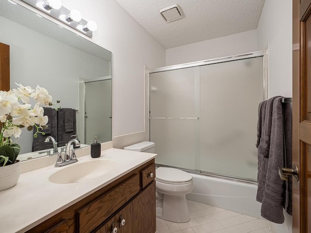 bathroom featuring tile patterned floors, toilet, a textured ceiling, bath / shower combo with glass door, and vanity