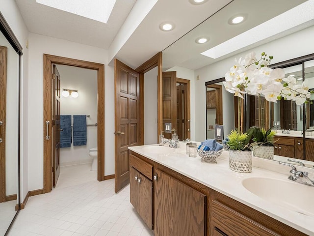 full bath featuring a skylight, toilet, and a sink