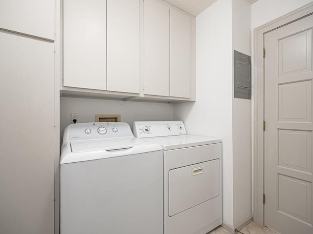 clothes washing area with washing machine and clothes dryer, cabinet space, and electric panel