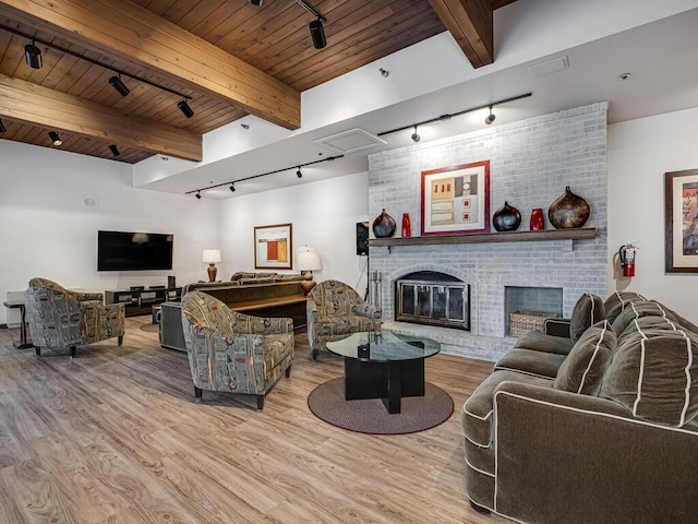 living room with beamed ceiling, a fireplace, wooden ceiling, and wood finished floors