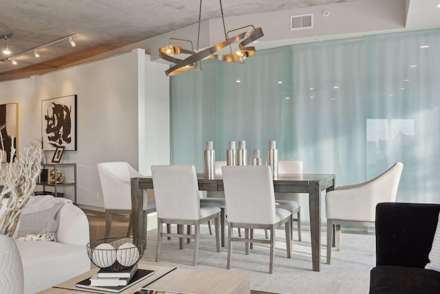 dining space with track lighting and a notable chandelier