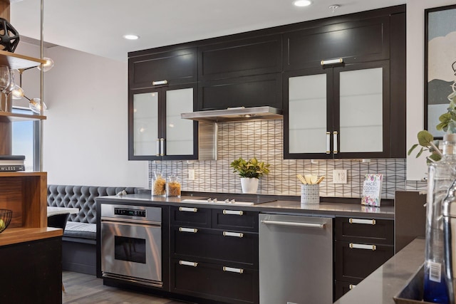 kitchen featuring pendant lighting, light hardwood / wood-style floors, oven, black gas cooktop, and backsplash