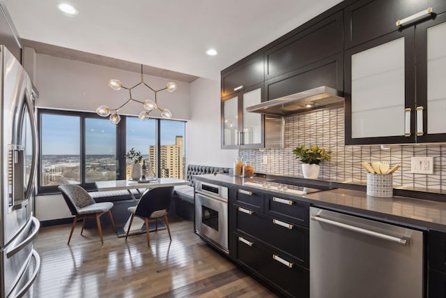 kitchen featuring a chandelier, stainless steel appliances, dark hardwood / wood-style flooring, pendant lighting, and backsplash