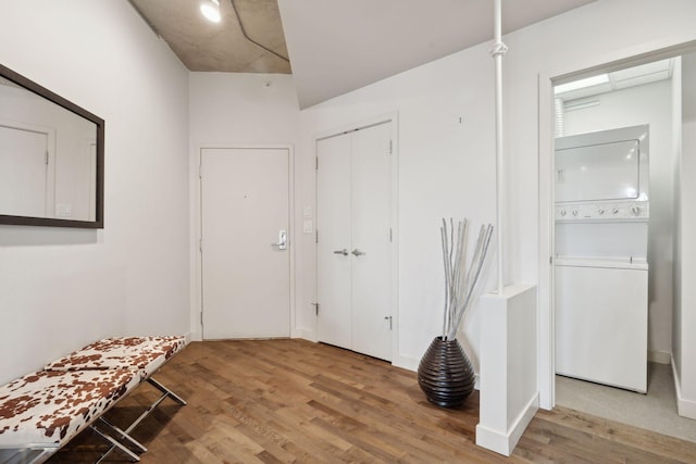 foyer with stacked washer and clothes dryer and hardwood / wood-style floors