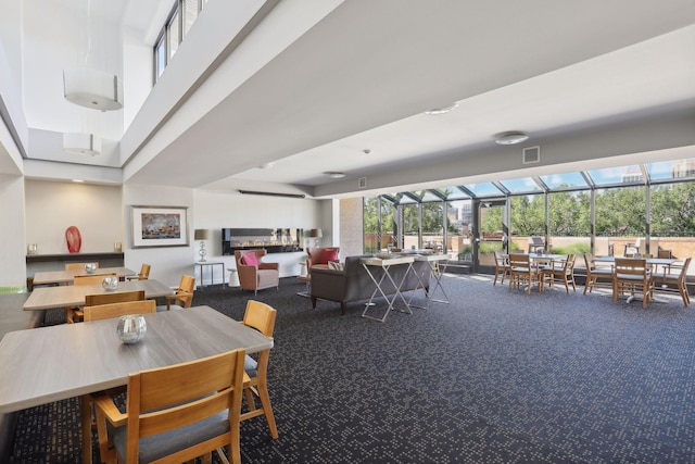 dining area featuring a towering ceiling, carpet floors, and a wealth of natural light