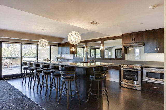 kitchen featuring stainless steel appliances, a notable chandelier, dark hardwood / wood-style floors, and dark brown cabinetry