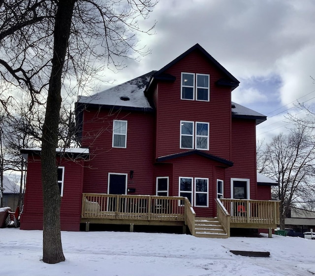 snow covered back of property with a deck