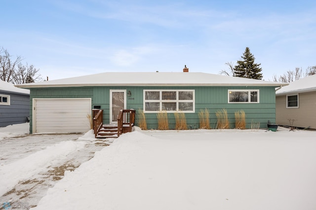 snow covered back of property featuring a garage