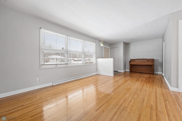 unfurnished room with baseboard heating and light wood-type flooring