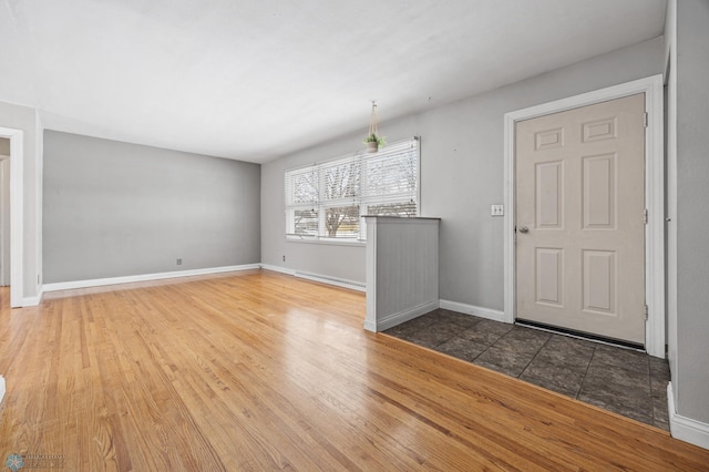 unfurnished living room with a baseboard radiator and hardwood / wood-style floors