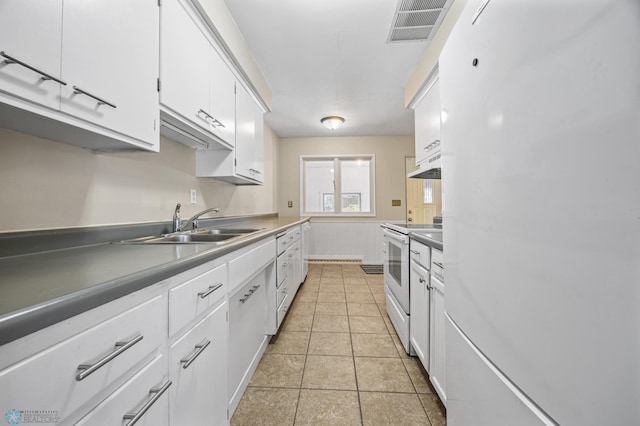 kitchen with white appliances, white cabinetry, sink, and light tile patterned floors