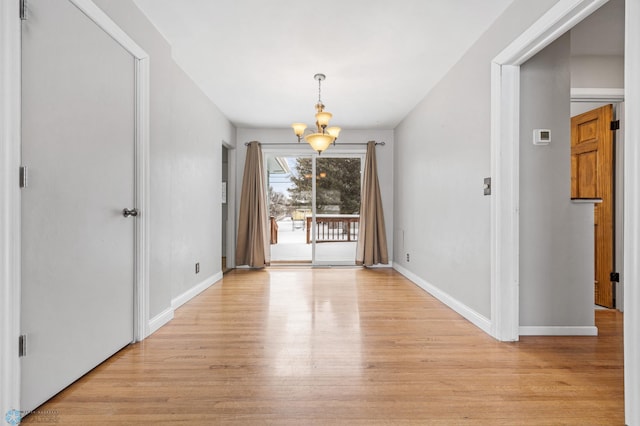 unfurnished dining area featuring a notable chandelier and light hardwood / wood-style flooring