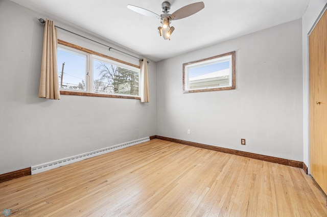 empty room with light hardwood / wood-style floors, ceiling fan, and a baseboard heating unit