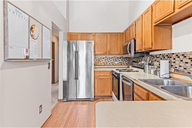 kitchen featuring appliances with stainless steel finishes, light hardwood / wood-style floors, tasteful backsplash, and sink